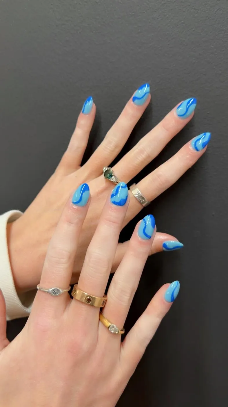 Nude almond nails with bright blue swirl nail art