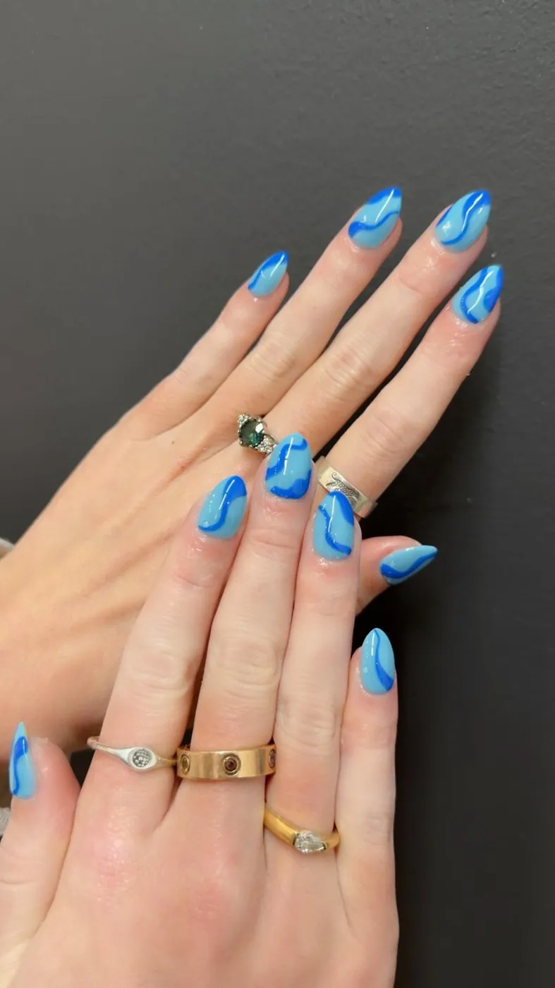 Blue swirl nail art on nude almond nails, a second angle