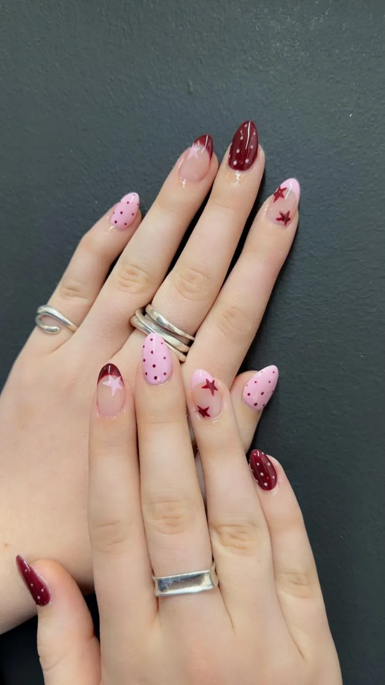 Burgundy and pink polka-dot nails with hand-painted stars, a second angle