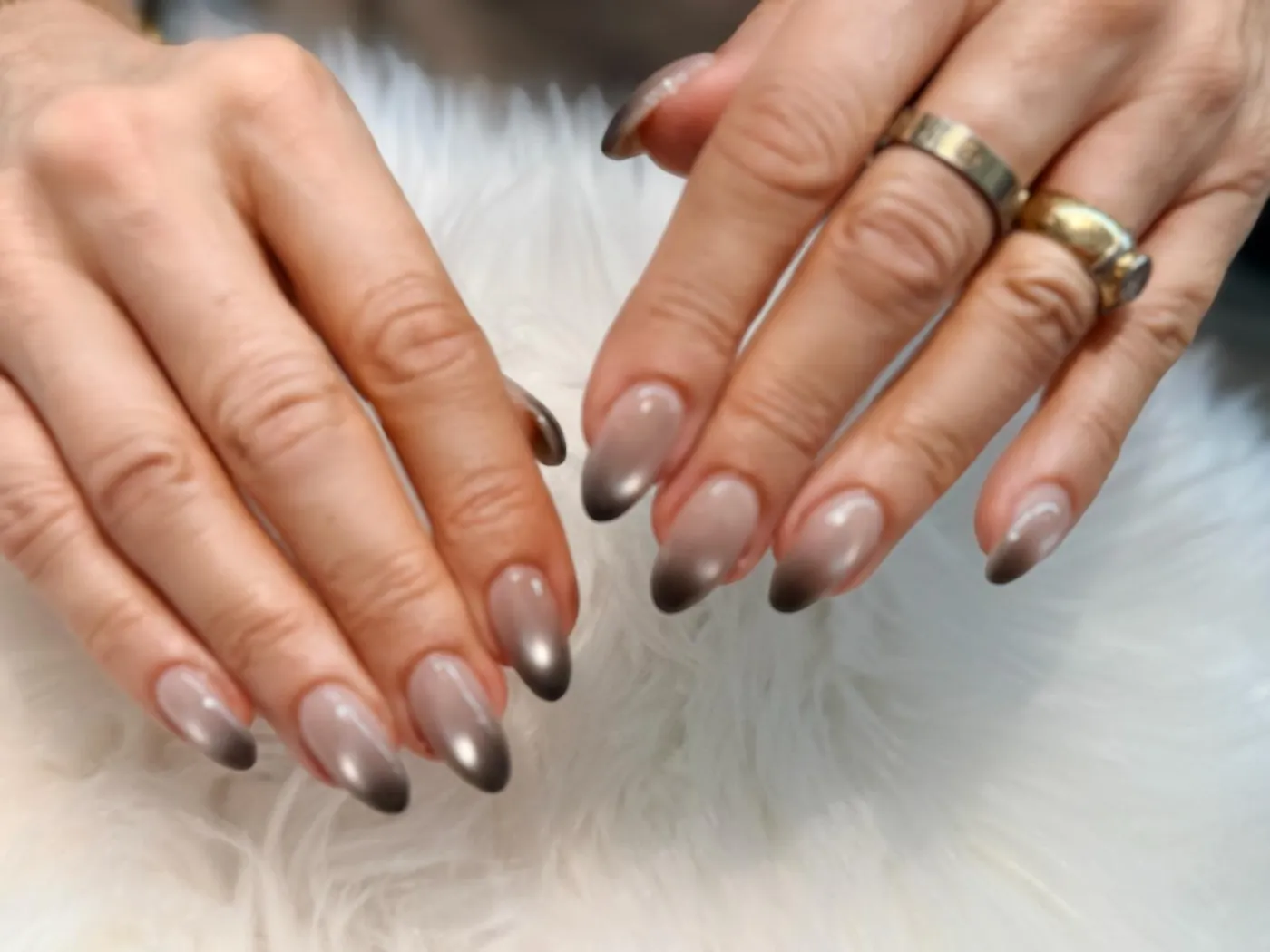 Long almond nails with a chrome ombré finish, photographed on white faux fur