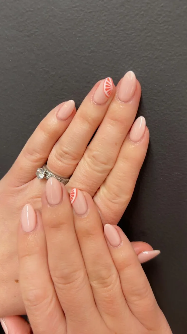 Soft nude almond nails with hand-painted orange citrus slice art on the accent nails