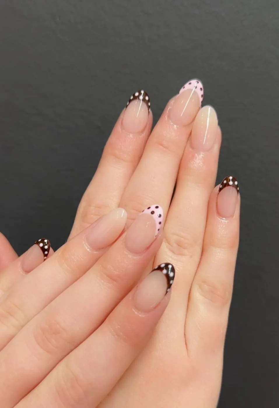 Nude almond nails with chocolate and pink polka-dot French tips