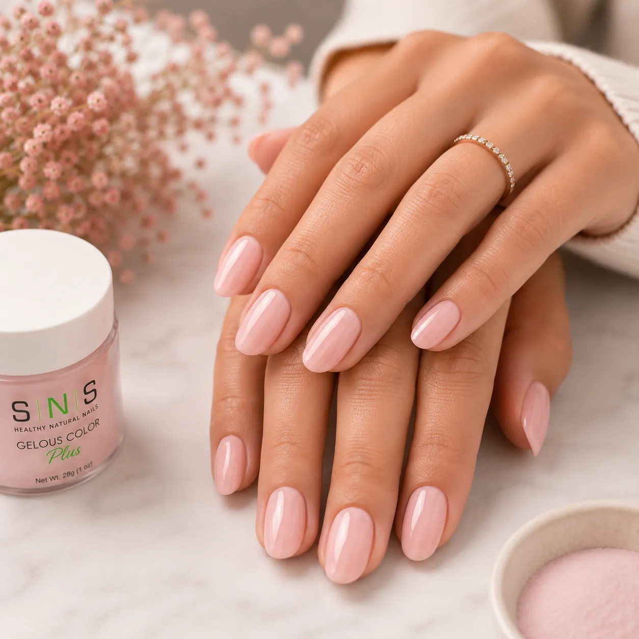 Glossy pink SNS dip powder nails beside a jar of SNS powder