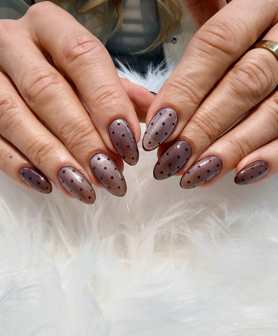 Close-up of sheer smoky plum almond nails with fine black polka dots
