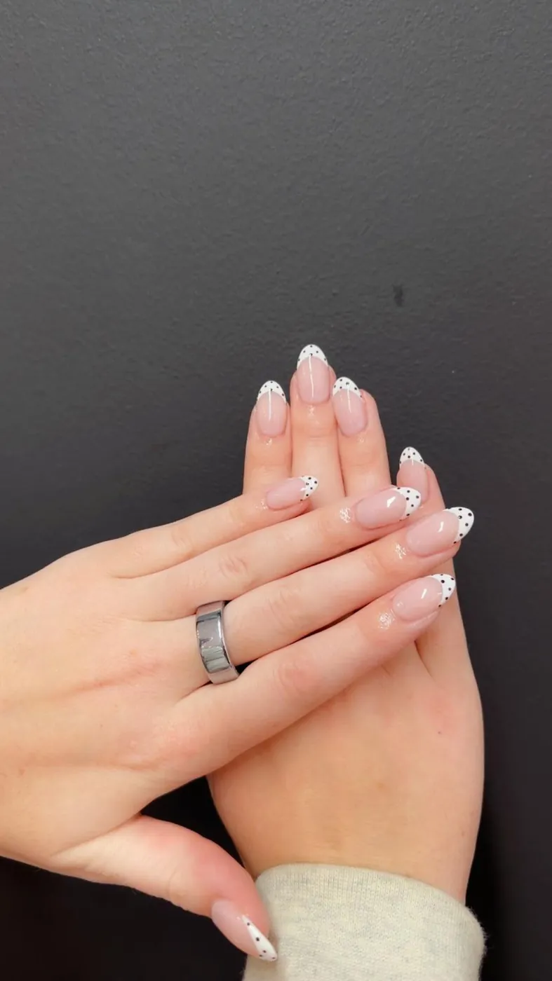 White polka-dot French tips on nude almond nails, a second angle